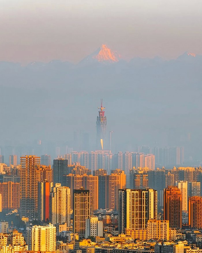 日光倾城，成都新高“峰”蜀峰468与身后的雪峰构成“双绝”。图片来源：嘉楠 摄