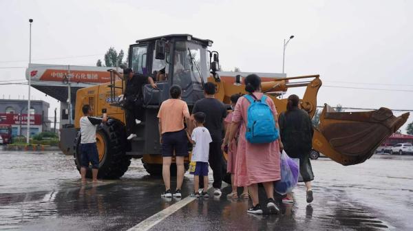 直击河南卫辉街头：道路积水超半米，铲车当“公交”运送居民