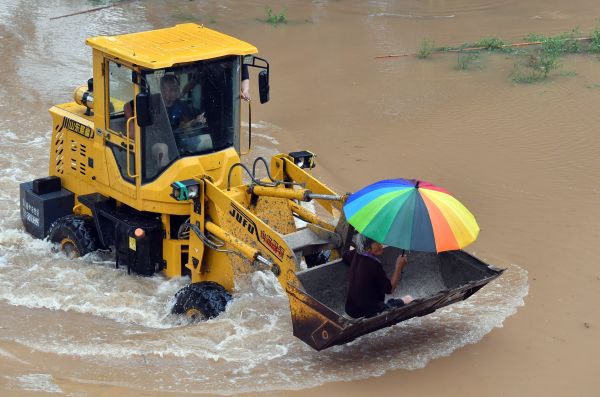 河南省近日多地遭受大暴雨、特大暴雨。图为7月22日，新乡市黄庄村一位村民坐上铲车转移。（李嘉南 摄）