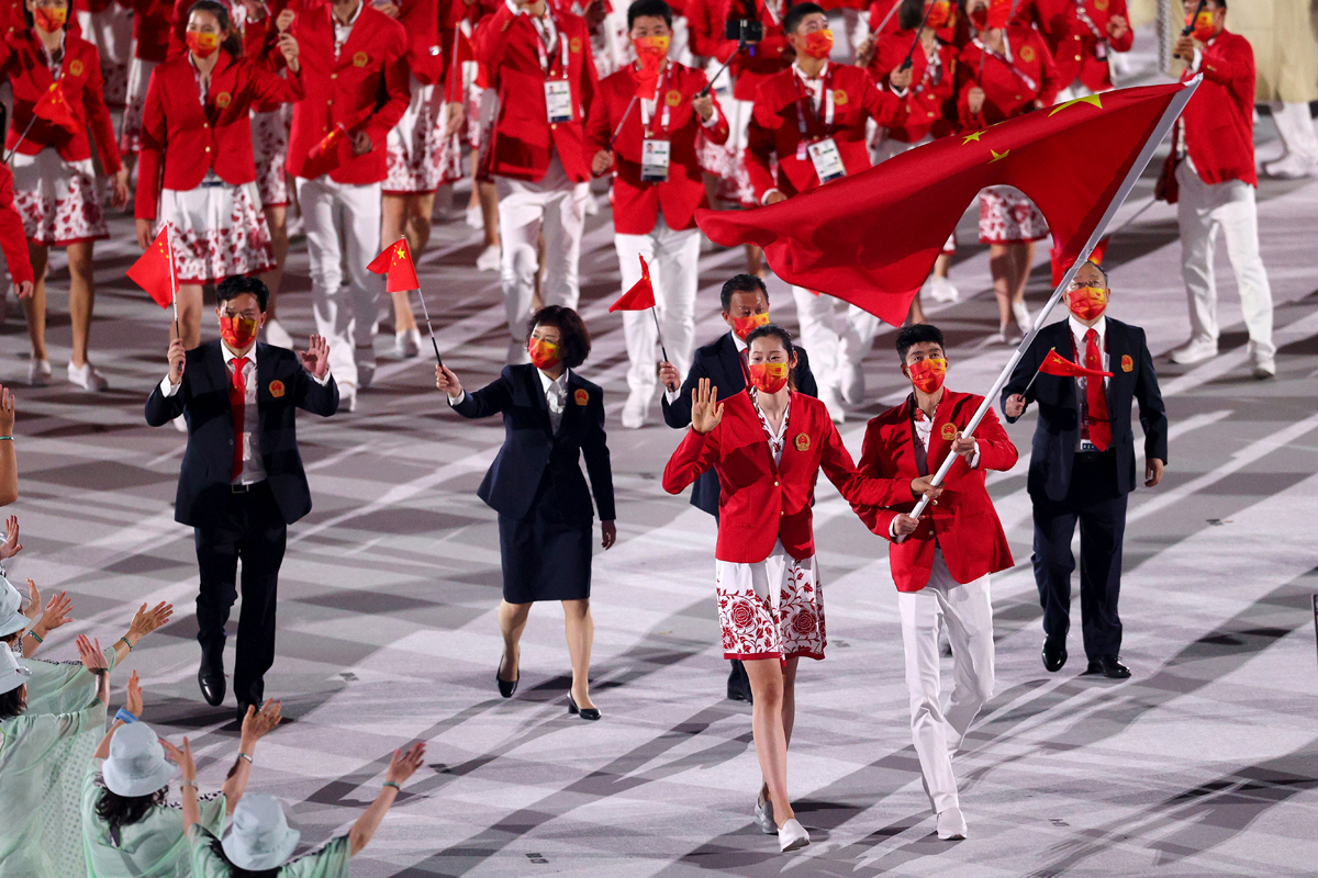 中国奥运会代表团成员身穿红白配色入场服，手挥五星红旗，由朱婷和赵帅引领入场。