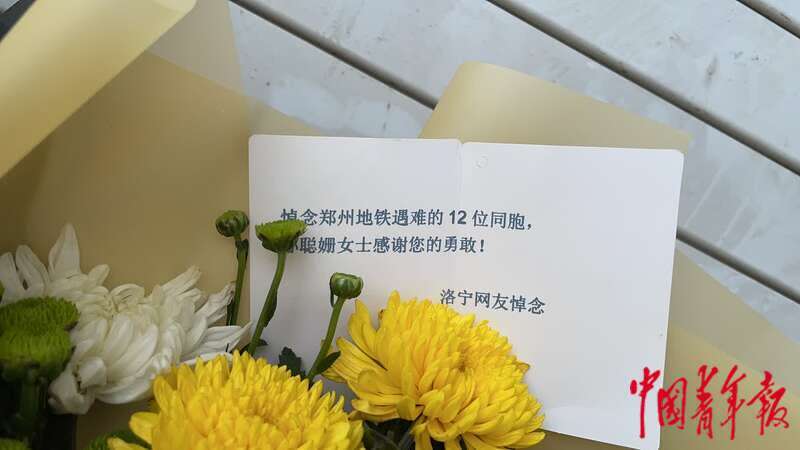 市民在郑州地铁5号线站口摆放菊花和糕点悼念遇难者