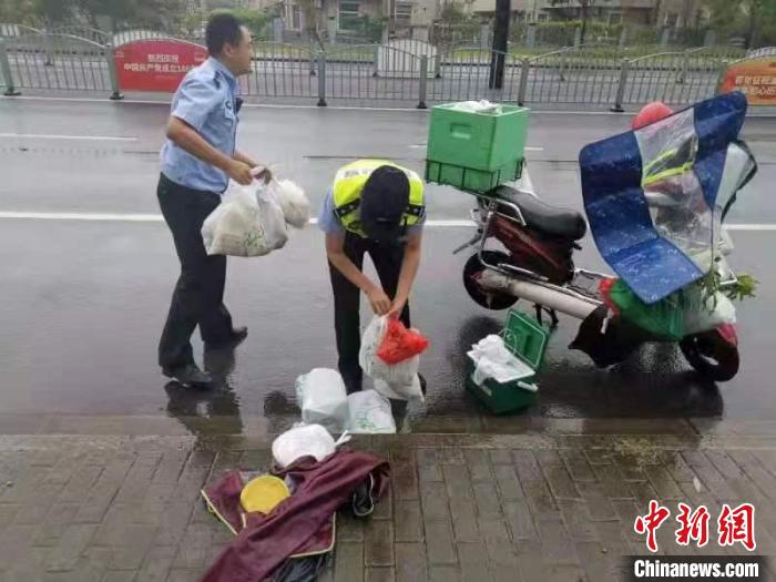 冒雨送货的外卖小哥电瓶车被风吹倒，警方协助捡拾掉落的外卖。上海松江警方供图