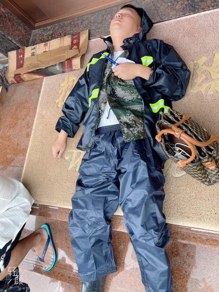 照片上一名穿着雨衣的男子席地睡着,手上还攥着一张纸和笔.