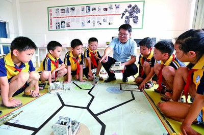 江西吉安市峡江县第二实验小学的老师（中）在指导学生调试机器人。陈福平摄/光明图片