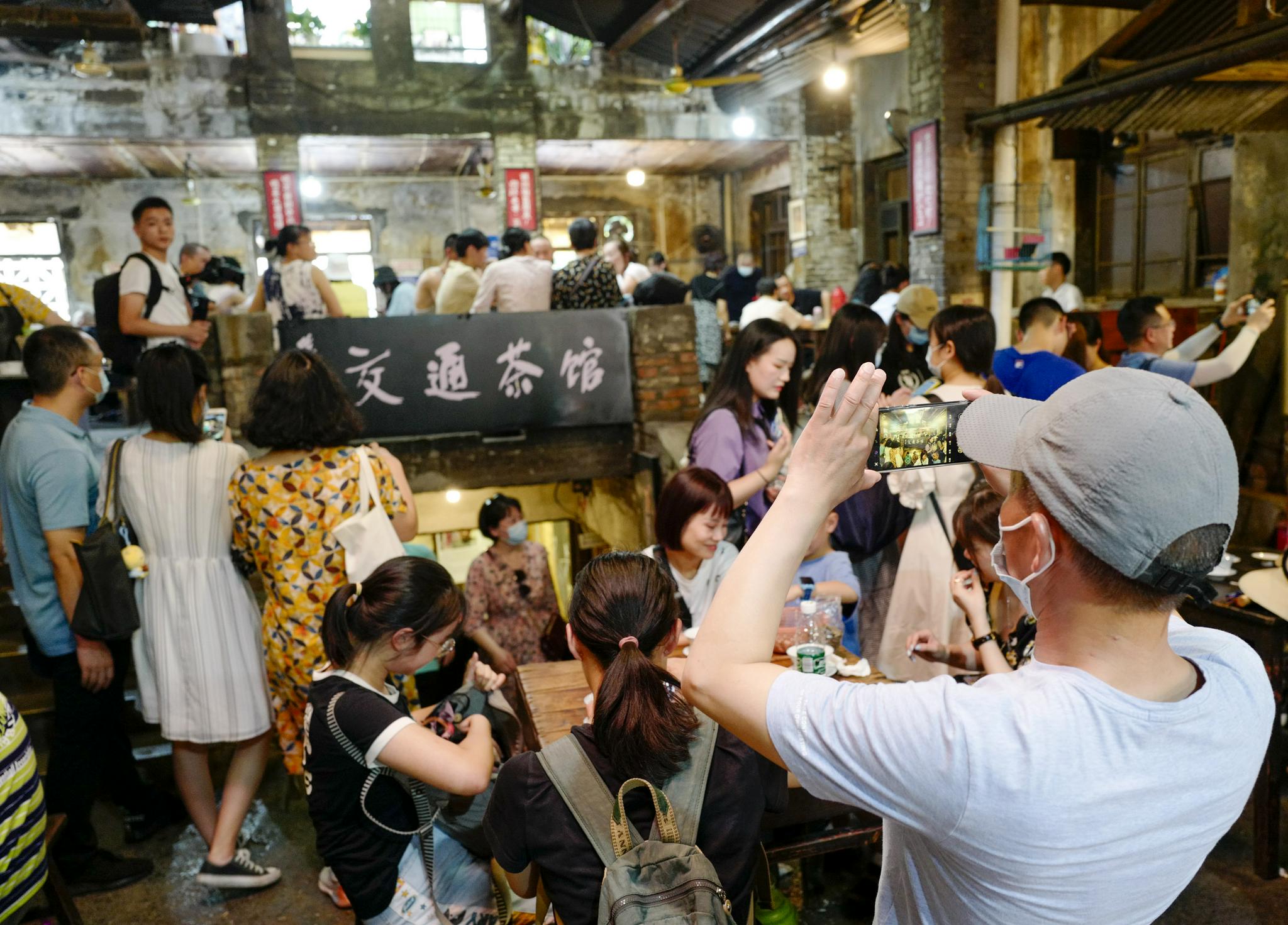 7月26日,在交通茶馆内,陈安健(右一)在进行油画创作.