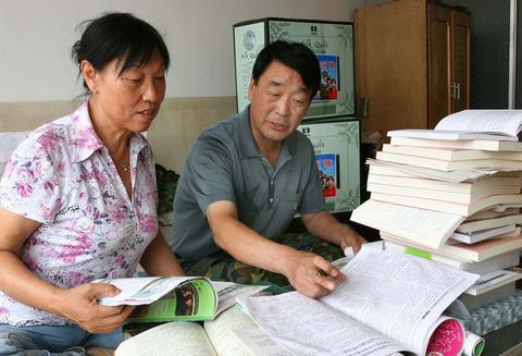 这是张连印和妻子一起查阅资料，学习植树造林和防风治沙知识（2007年9月1日摄）。新华社 刘松峰摄