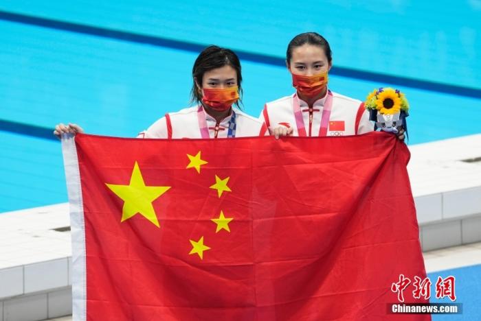 东京奥运会女子单人3米板跳水颁奖仪式，中国队包揽金银牌。图为金牌得主施廷懋(左)与王涵(右)手持国旗合影。中新社记者 杜洋 摄