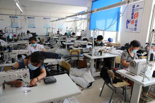 服装加工厂里的流水线女工们正忙着赶制一批儿童背带棉裤.