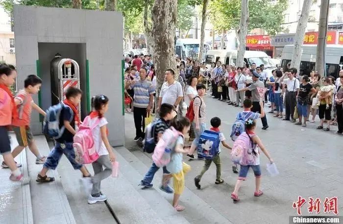 资料图：武汉一小学门外等待学生放学的家长们。中新社发 张畅 摄