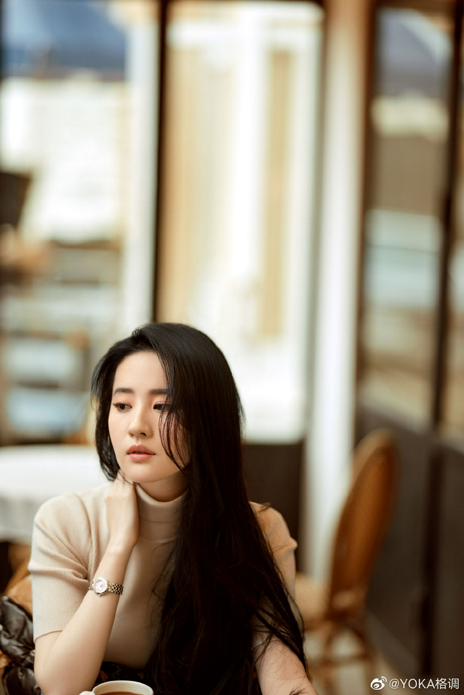 照片中,刘亦菲长发自然散落,米色针织衫衬托出优雅干练,随手撩发动人