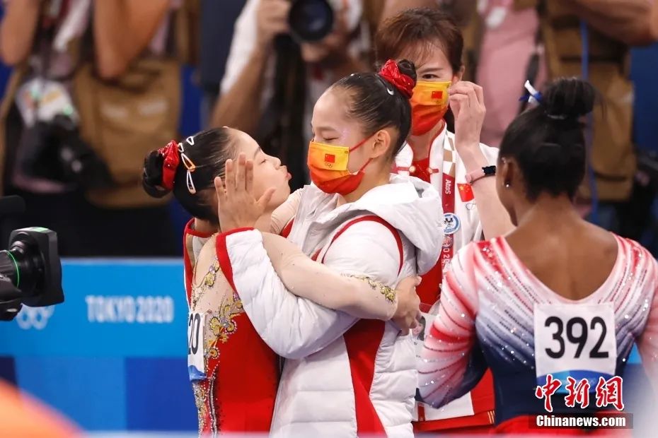 北京时间8月3日，中国选手管晨辰在东京奥运会女子平衡木决赛中夺得冠军。图为管晨辰（左）与队友拥抱亲亲。中新社记者 富田 摄