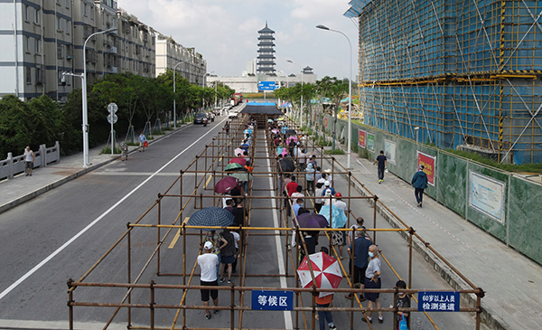 市民在江苏省扬州市广陵区汤汪乡杉湾花园社区核酸检测点排队等候核酸