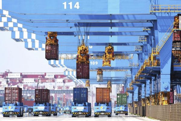 在山东青岛市的一处货运港口，龙门吊车正将集装箱装载到运输车上。（美联社）