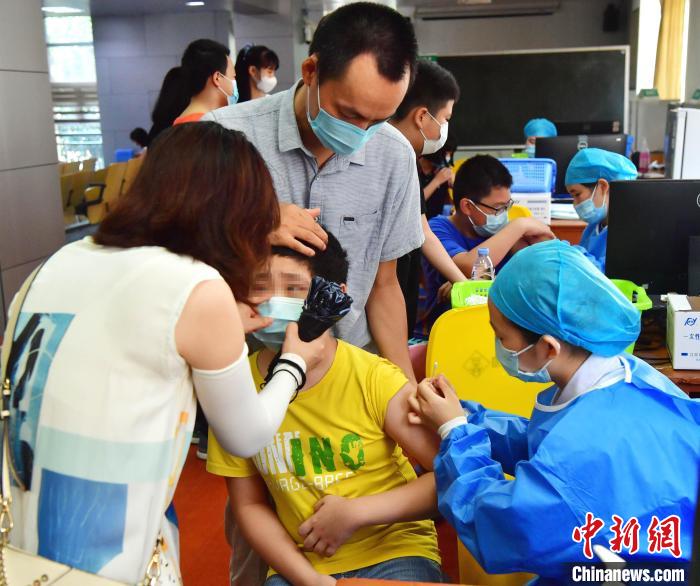 图为福州市高湖小学老师鼓励一位正在接种新冠疫苗的学生。　张斌 摄
