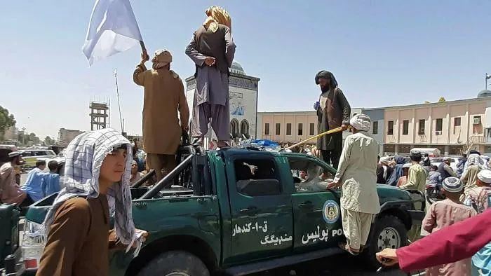 塔利班武装分子爬上坎大哈一辆损坏的警车图源：外媒