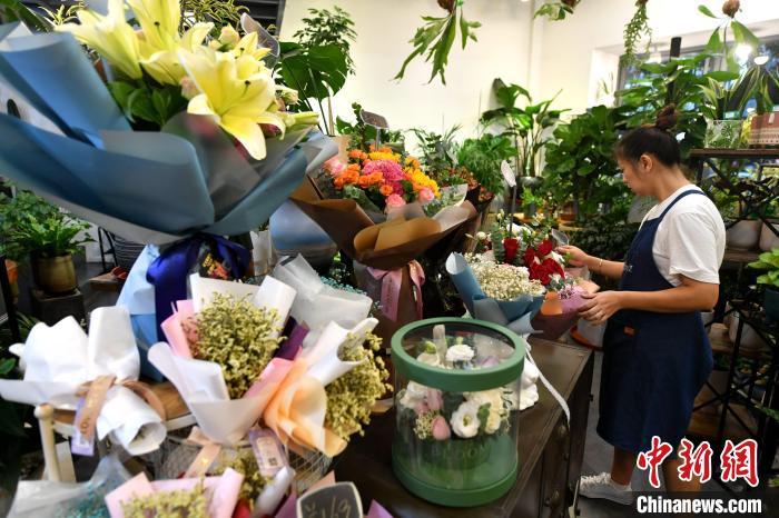 随着七夕(8月14日)“情人节”临近，福州不少商家积极备货抢占七夕鲜花市场。图为店员正在整理花束。吕明 摄