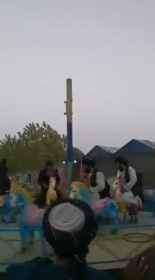 塔利班士兵游乐园内玩碰碰车：手握长枪 欢呼大笑休闲区蓝鸢梦想 - Www.slyday.coM