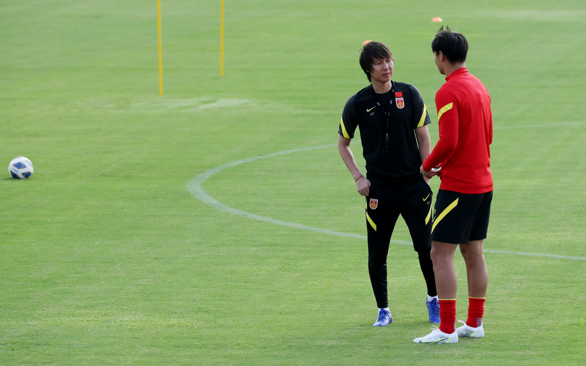 8月18日，国足主帅李铁（左）在训练中与队员交流。图/新华社