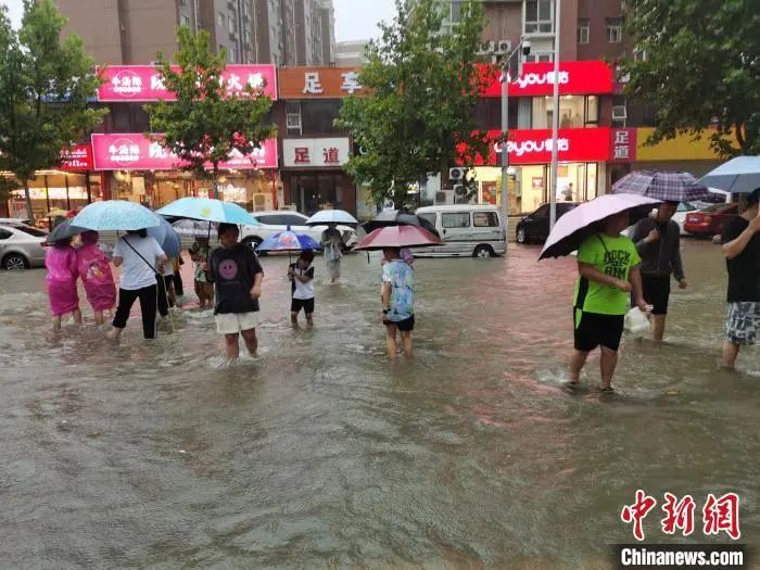 资料图：郑州7·20特大暴雨后，市民在街道上趟水而过。王登峰 摄