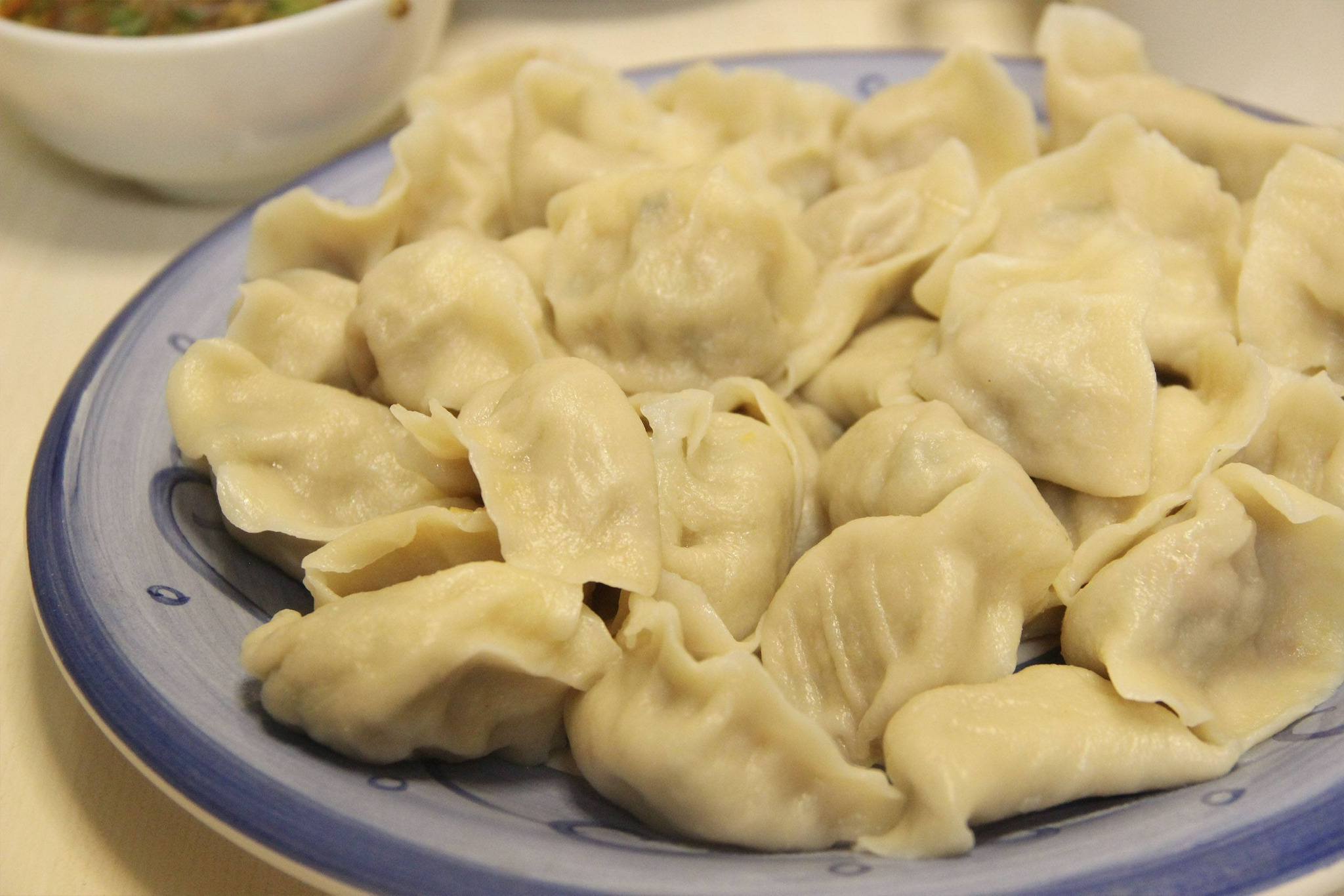 7,用小勺子舀出适量的馅料,包入饺子皮里面,制作成羊肉水饺,然后把水