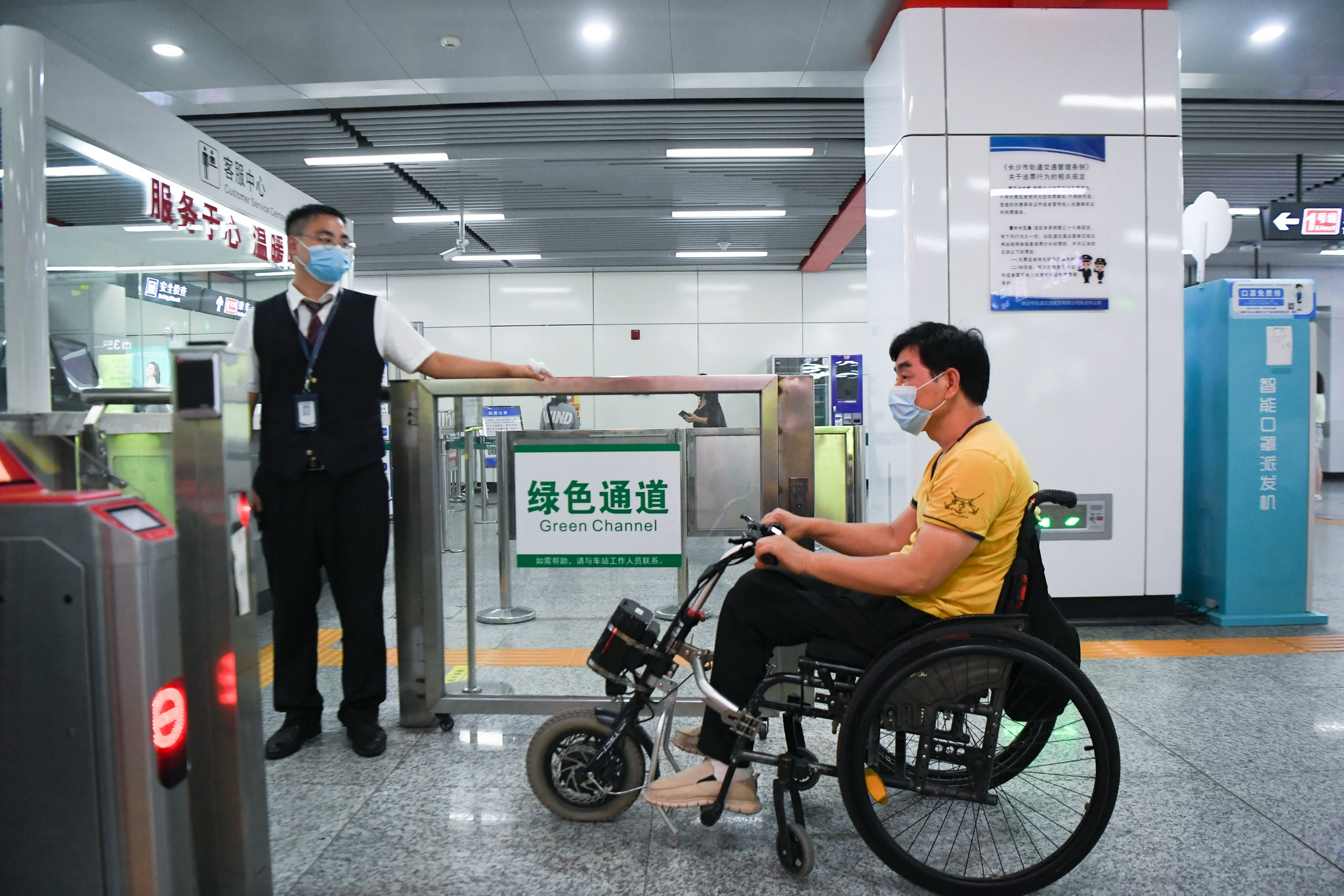 8月25日,伍树林(右)在湖南省长沙市桂花坪地铁站通过绿色通道进站乘车