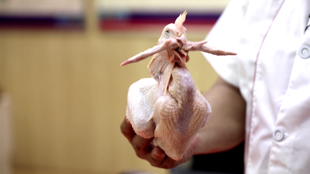 工人们会对每只鸡"别腿别翅",最终呈现口衔羽翎,鸭浮水面的造型