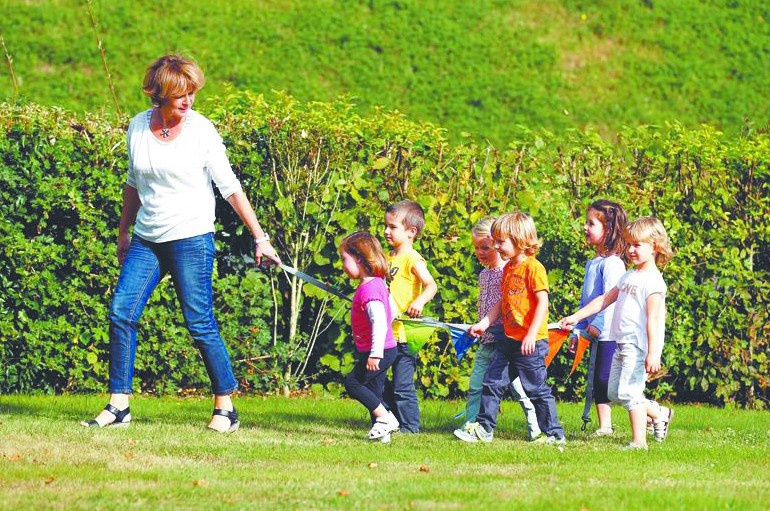 幼儿园老师用绳子拉着孩子们去户外活动.