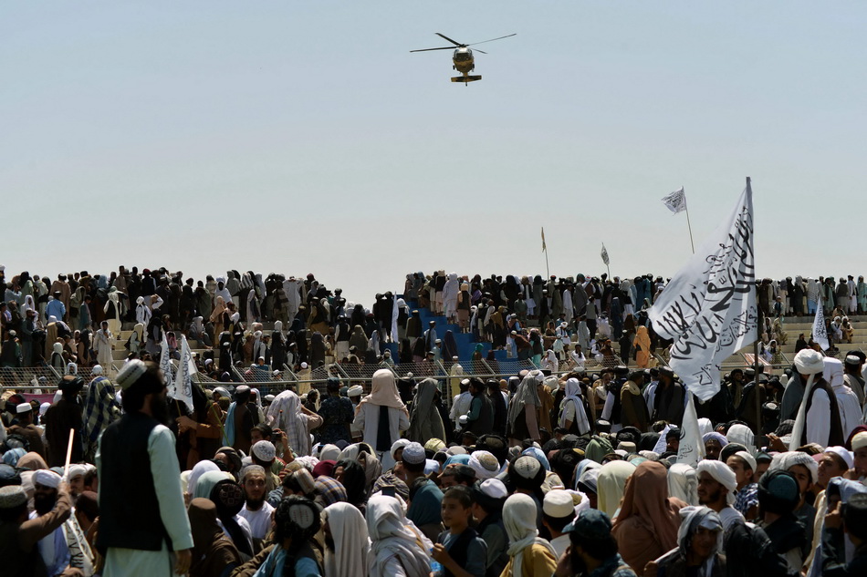 当地时间2021年9月1日，塔利班支持者聚集在坎大哈，一架直升机从上空飞过。