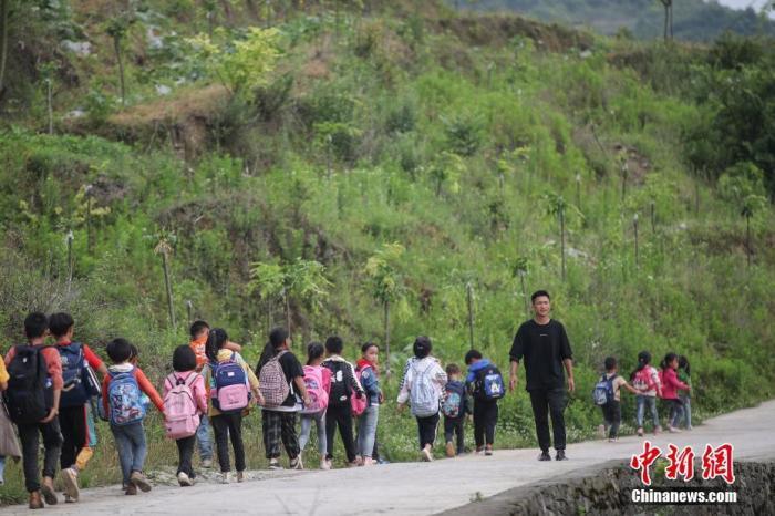 资料图：一名“90后”乡村教师组织学生排队上下学。 中新社记者 瞿宏伦 摄