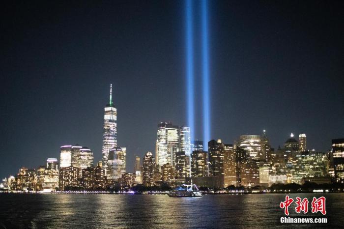 当地时间9月10日夜间，从美国纽约哈德逊河上航行的轮船上眺望曼哈顿，两根象征世贸中心双子塔的蓝色光柱正在进行测试。 中新社记者 廖攀 摄