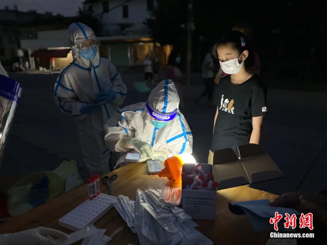 天已黑，路灯未亮。在仙游县枫亭镇建国村核酸检测点，一位女孩等待采集核酸。陈其华 摄