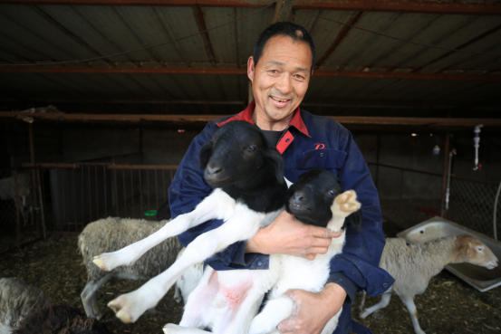 图为李顺一抱着小羊羔露出开心的笑容.