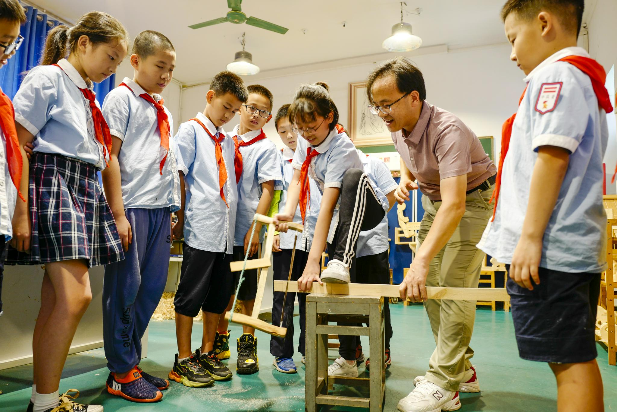 在铁路小学的操场上,小鲁班社团成员在老师的指导下维修学校破损的木