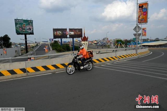 资料图：疫情下的柬埔寨金边，一名食品配送员在空荡荡的马路上行驶。