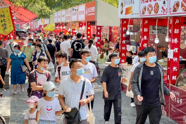 国庆长假期间各地消费市场活力涌动。图为2日游客在武汉市著名的小吃街户部巷休闲消费。（肖艺九 摄）