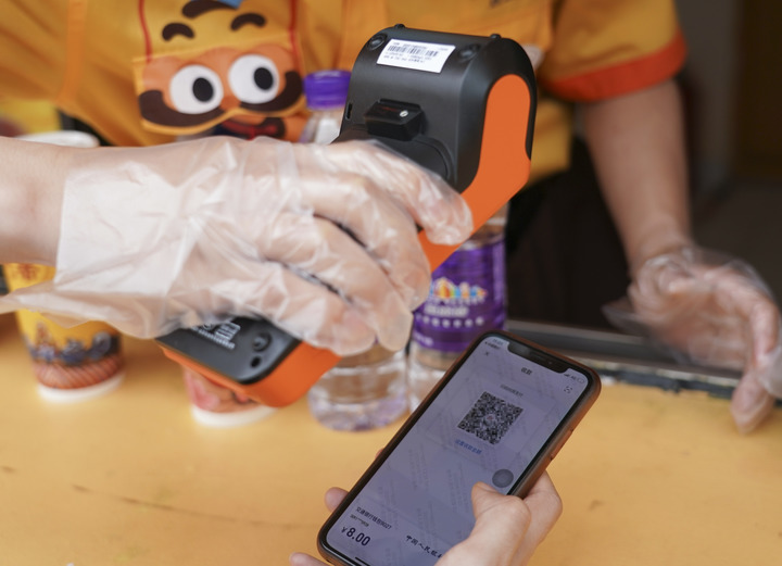 图为2021年6月16日，北京欢乐谷一商户使用POS机对使用数字人民币的消费者进行扫码收款。新华社记者 陈钟昊 摄