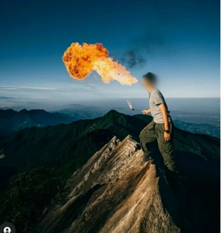 一男子站在“鸢嘴山”山顶尖石上表演喷火特技。图自台湾“联合新闻网”