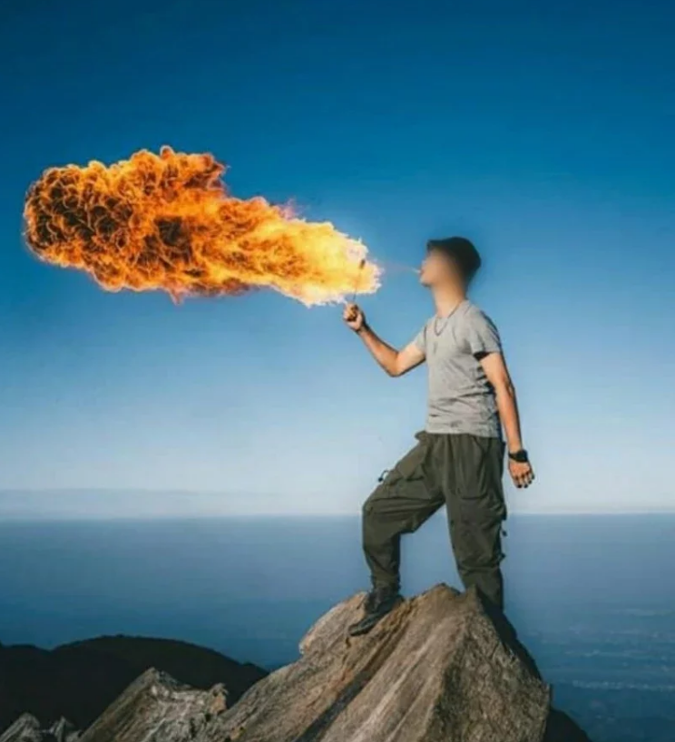 一男子站在“鸢嘴山”山顶尖石上表演喷火特技。图自台湾“联合新闻网”