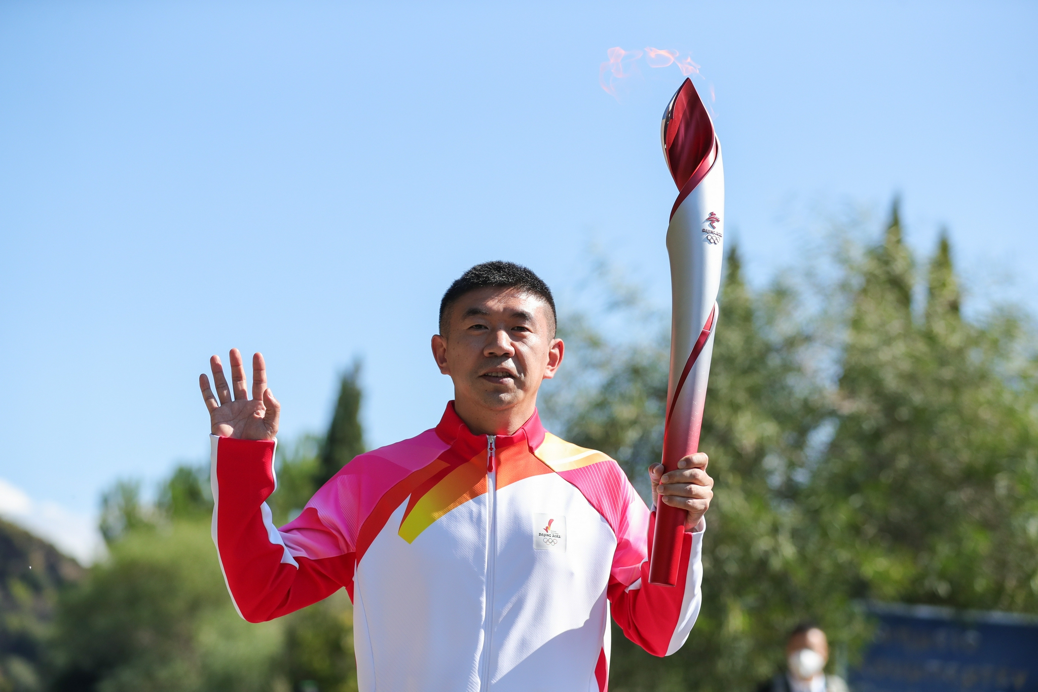 短道速滑运动员李佳军手持北京冬奥会火炬飞扬在火种采集成功后传递