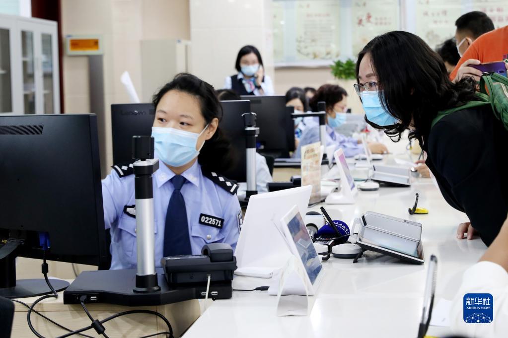 2020年10月14日，原籍浙江湖州的王秀丽（右）在上海市徐汇漕河泾社区事务受理服务中心公安综合窗口办理户口迁移手续，成为享受上海市公安局会同浙江省公安厅共同推出的沪浙“跨省市户口网上迁移”便民措施的第一人。新华社记者 方喆 摄