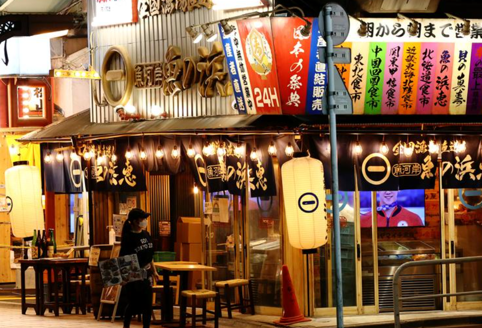 日本东京，一家饭店的服务员在店外迎客。来源：路透社
