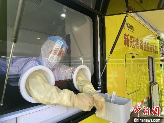 资料图：新冠病毒核酸检测“小黄车”的工作人员正在开展核酸采集工作。陈晟 摄