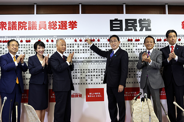当地时间2021年10月31日，日本东京，日本首相岸田文雄把小红花放在胜选议员的名字上。人民视觉  图