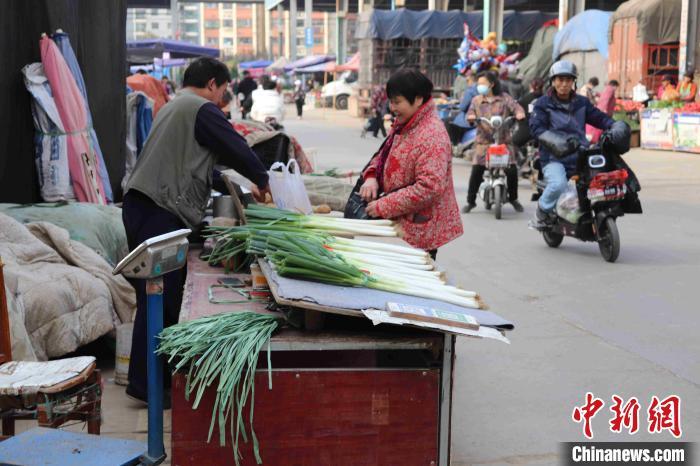 市民在农贸市场挑选大葱，询问葱价。李明芮 摄