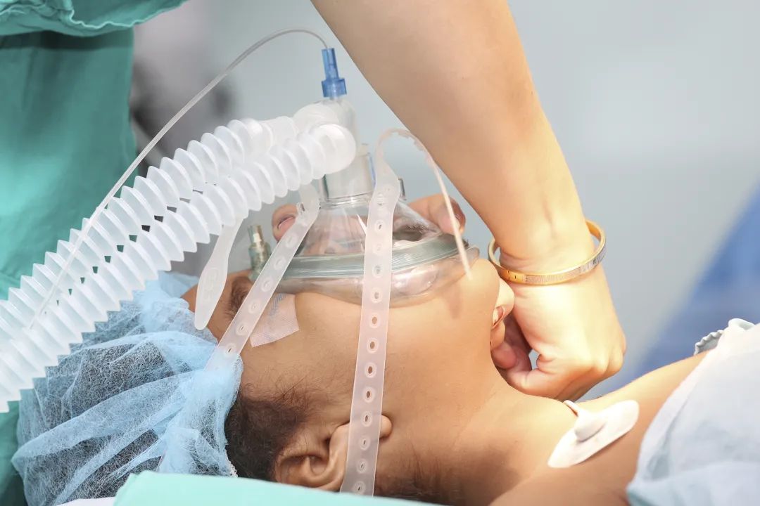 身上连着监护仪,吊着输液瓶,盖着氧气面罩,麻醉还没完全醒,左边脸上挂