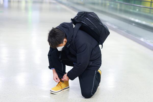 黄磊穿工装外套甩臂疾走似"干部" 背双肩包蹲地系鞋带接地气