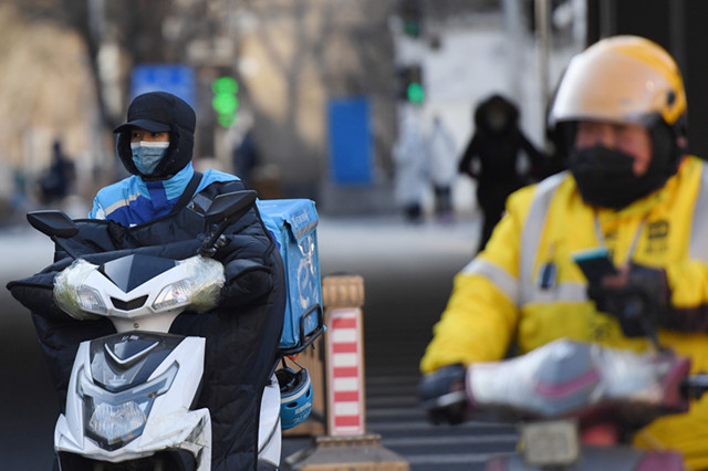  1月6日，外卖小哥穿着御寒服装，在北京市朝阳区国贸附近骑行。新华社。