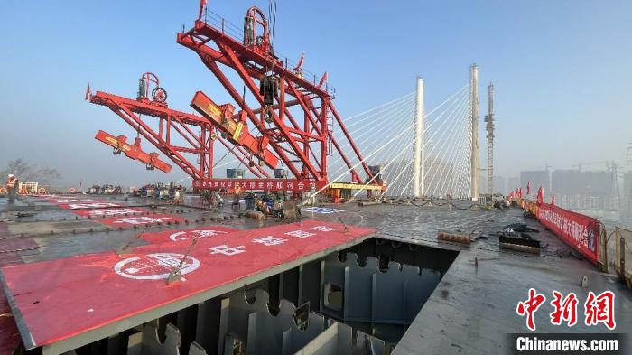 施工人员正在将一块长8.3米、宽60米、重约300吨的桥面板吊装至指定位置。陈于飞 摄