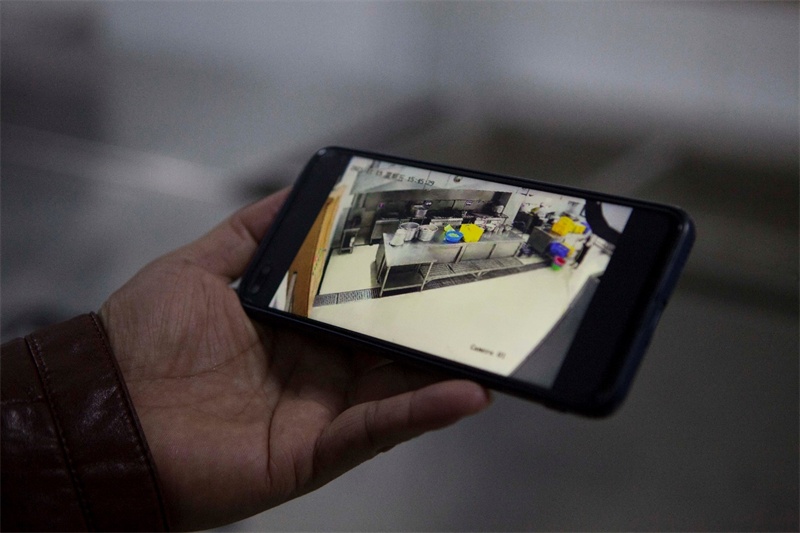 田东县第四中学副校长通过手机调取明厨亮灶摄像头监控画面(央广网发