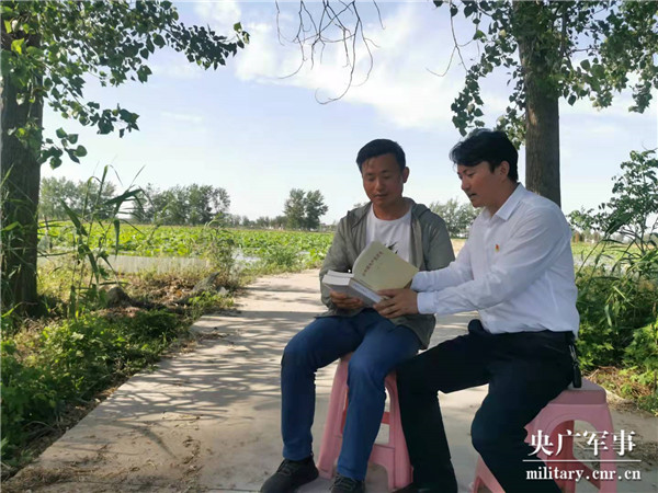 卢攀峰(右)给村民讲党史(朱荫桃 摄)卢攀峰(中)